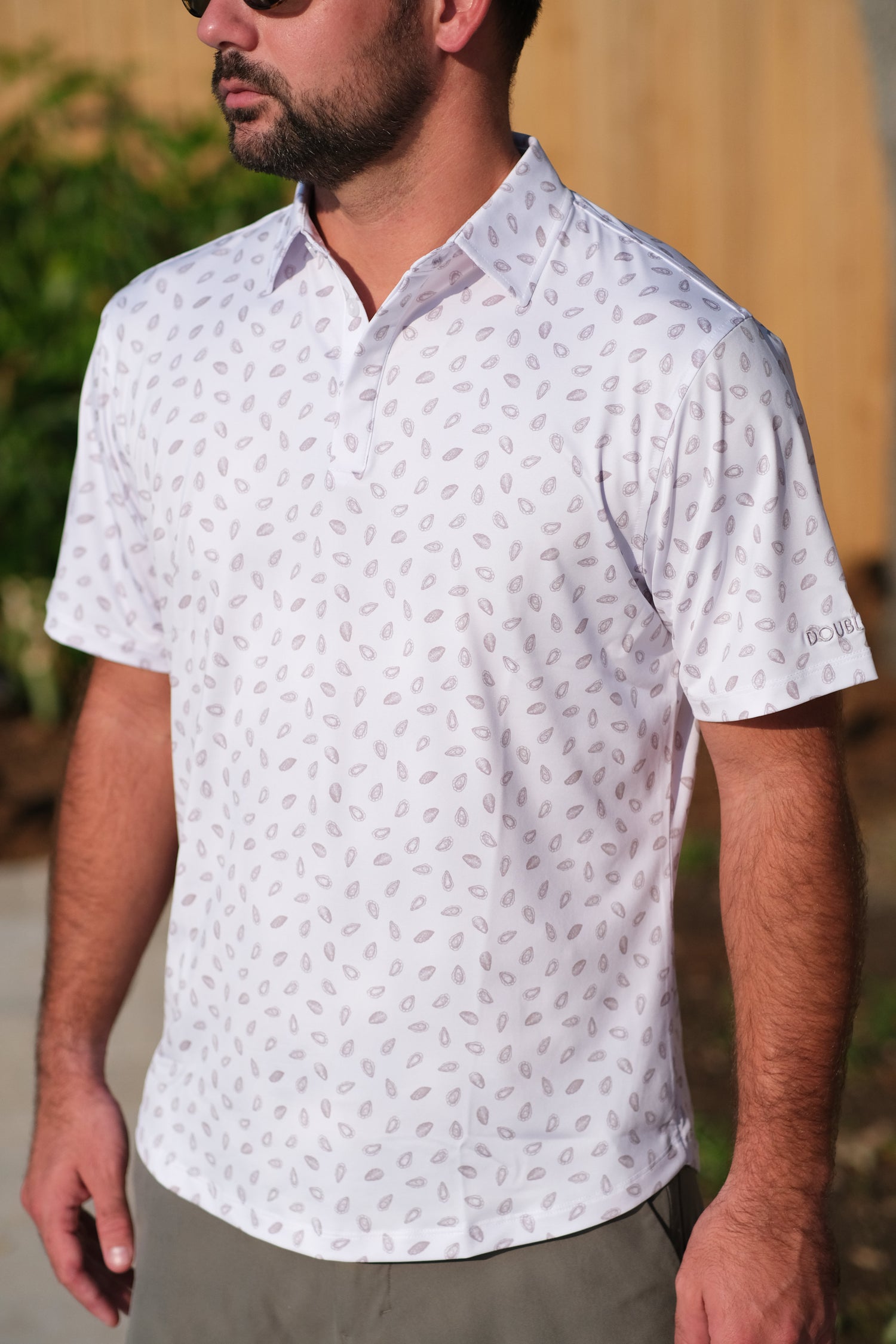 Man wearing a white  shirt with a grey oysters pattern outdoors